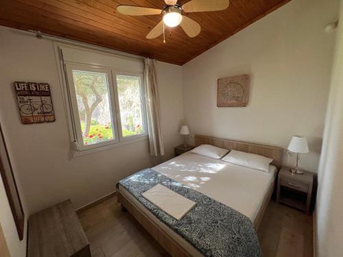 a bedroom with a bed with a ceiling fan and a window at Kallithea in Iraklitsa
