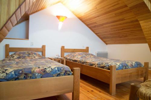 deux lits dans une chambre avec plafonds en bois dans l'établissement Gîte Gîtes de France 3/4 personnes à Ferluguet, à Sainte-Eulalie