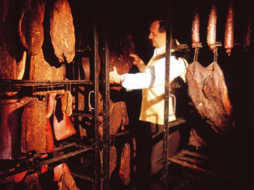 a man standing in front of a rack of meat at Landgasthof Jagerwirt in Volders