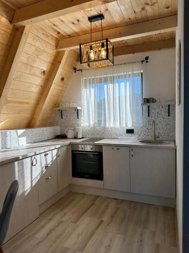 a large kitchen with white cabinets and a chandelier at Monte zone in Žabljak