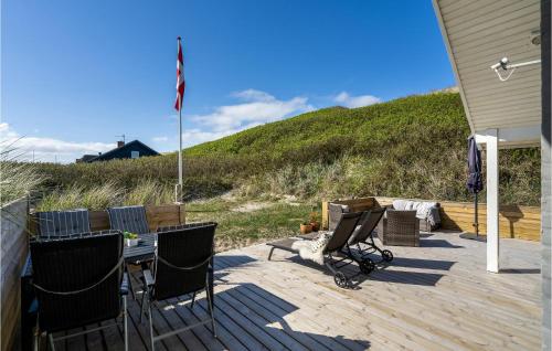 a deck with chairs and a table and a flag at Stunning Home In Ulfborg With Kitchen in Ulfborg
