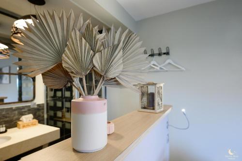 un vase avec une plante sur un comptoir dans une salle de bains dans l'établissement Les Pins Perdus, à Saint-Ciers-dʼAbzac