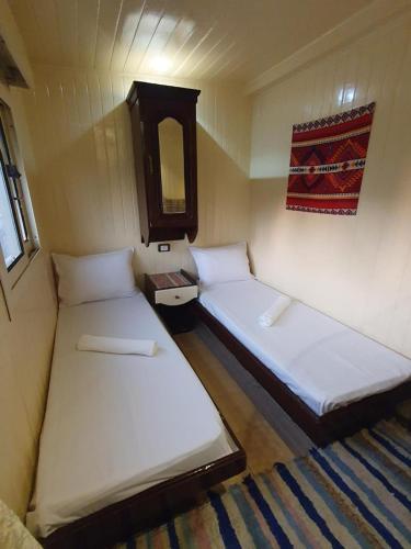 two beds in a small room with a mirror at Moon Boat in Luxor