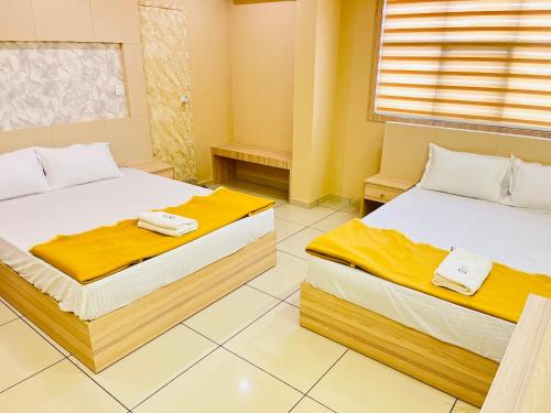 two beds in a room with yellow walls at Famstay and healthclub in Kannur