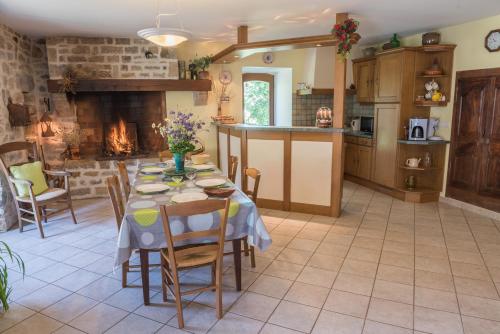 Il comprend une cuisine et une salle à manger avec une table et une cheminée. dans l'établissement Gîte Gîtes de France 3 épis 6/7 pers aux Salelles, à Les Salelles