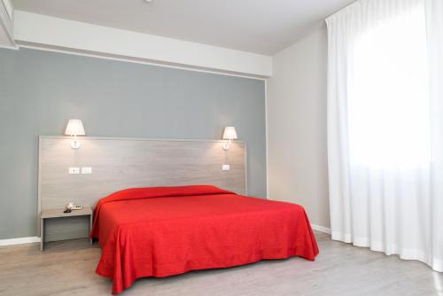 a red bed in a white room with a red blanket at Hotel Al Prato in Padova