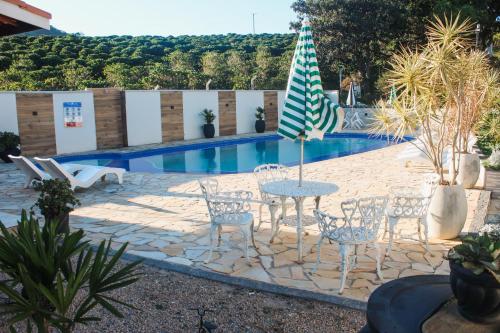 a patio with a table and chairs and an umbrella at Chalé Alto da Serra SP in Serra Negra