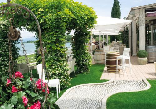 a garden with a table and chairs and flowers at Hotel Aquila D'Oro Desenzano in Desenzano del Garda