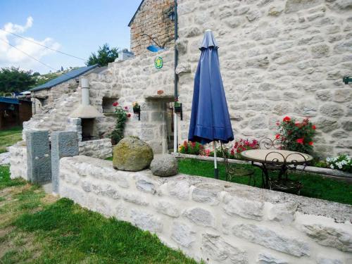 un parapluie bleu posé à côté d'un bâtiment en pierre dans l'établissement Gites de france 2 pers aux laubies, à Saint-Étienne-du-Valdonnez