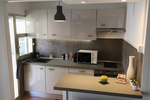une cuisine avec des placards blancs et un comptoir avec un four micro-ondes dans l'établissement Appartement Cannes quartier des Anglais, à Cannes