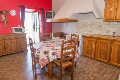 d'une cuisine avec une table, des chaises et des murs rouges. dans l'établissement Gîte Gîtes de France 4/6 personnes aux Laubies, à Saint-Étienne-du-Valdonnez