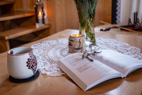 a book on a table with a cup and a candle at HRYCÓWKA Domki z Widokiem in Grywałd