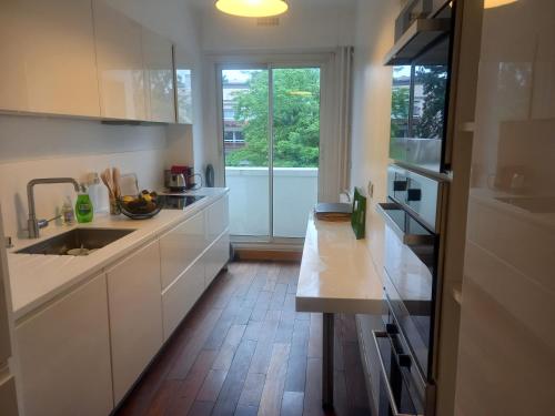 une cuisine avec des armoires blanches, un évier et une fenêtre dans l'établissement superbe appartement 120m2 Paris - Neuilly sur seine, à Neuilly-sur-Seine