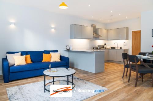 a living room with a blue couch and a kitchen at Two Bedroom Apartment At Buonomo Stays Short Lets & Serviced Accommodation close to Wimbledon Tennis Courts in London