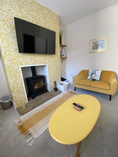 a living room with a table and a fireplace at Sea Biscuit Cottage, Scarborough in Scarborough