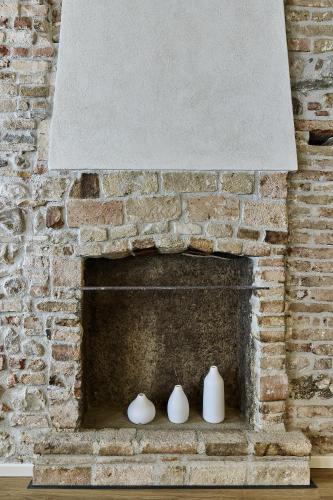 a brick fireplace with three white vases on it at SARPI Apartment & Suite in Udine