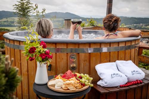 two women in a hot tub with a plate of food at HRYCÓWKA Domki z Widokiem in Grywałd