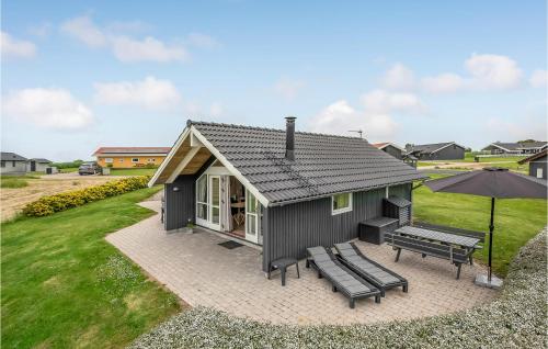 a small black cottage with two benches and an umbrella at Three-Bedroom Holiday Home In Nordborg in Nordborg