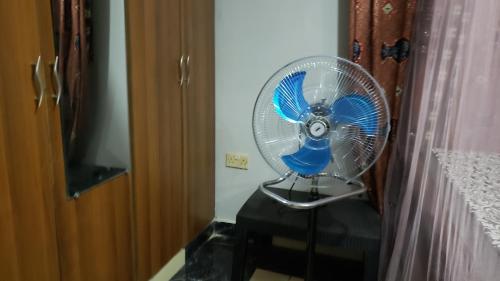 a blue fan sitting on a table next to a door at African Taste Guest House. in Kitende