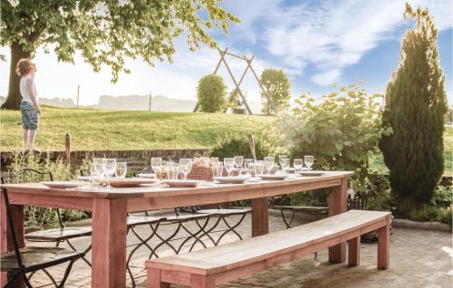 a wooden picnic table with glasses and a woman in a field at Seven-Bedroom Holiday Home In Remersdaal in Remersdaal