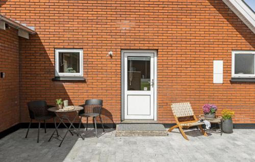 a red brick building with a white door and chairs at Nice Home In Thyholm With Wifi in Thyholm