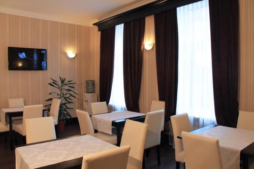 a restaurant with tables and white chairs and a window at Hotel Business Apartments in Dnipro