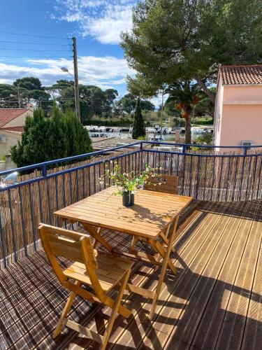 une table et des chaises en bois sur une terrasse dans l'établissement T2 Ayguade HYERES 83, à Hyères