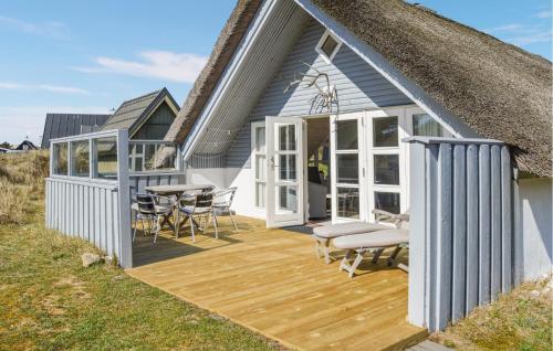 una casa con terraza con techo de paja en West-Side, en Søndervig
