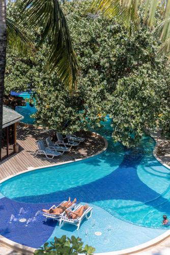 two people laying on lounge chairs in a swimming pool at Paradise Beach Hotel & Resort in West Bay