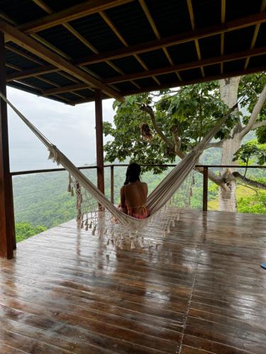 a woman sitting in a hammock on a porch at Paraiso Ahimsa in Buritaca