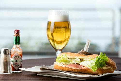 a sandwich on a plate with a glass of beer at Hotel Aquila D'Oro Desenzano in Desenzano del Garda