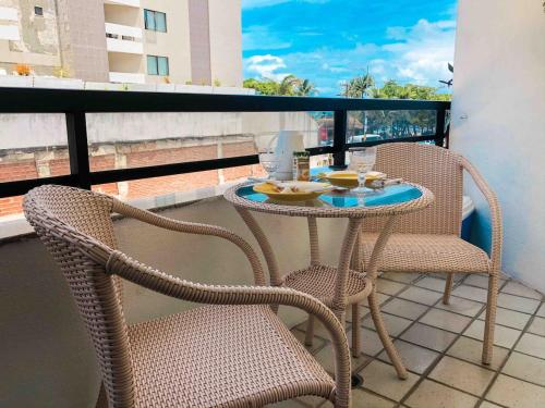 Un balcón con dos sillas y una mesa con comida. en TENERIFE - 107 · T-07: Beira mar da Pajuçara Piscinas Naturais, en Maceió