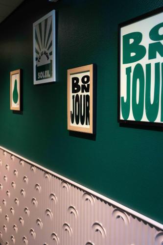 a green wall with some signs on the wall at Hôtel Argia in Hasparren