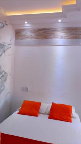a white bed with two orange pillows on it at Biomas Hotel in Brotas