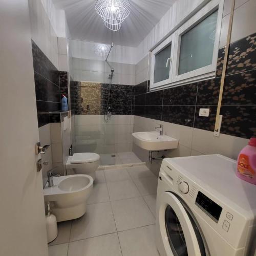 a bathroom with a toilet sink and a washing machine at Peonia Villa ValaMar in Draç