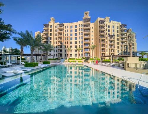 a swimming pool in front of a large building at Luxe & Comfy Madinat Jumeirah - Apartment with Scenic Views - Pool Managed by SunnyHomes in Dubai