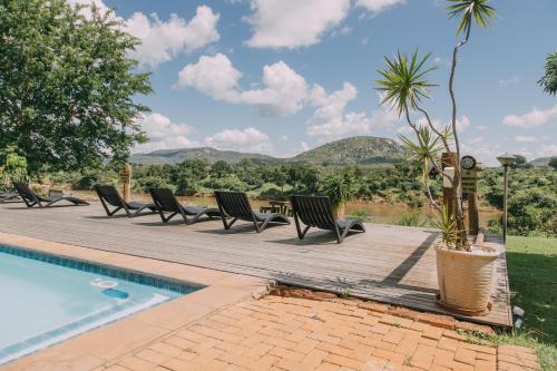 a deck with chairs and a table and a pool at Kruger View Chalets in Malelane