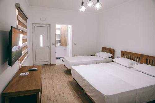 a room with two beds and a tv in it at Cereni Guesthouse in Berat