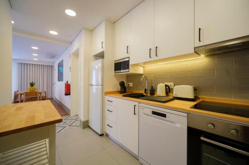a kitchen with white cabinets and a white refrigerator at Azimute 3 - T2 Moderno Centro Histórico Angra in Angra do Heroísmo