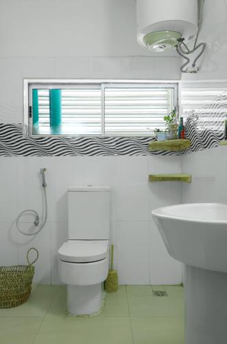a bathroom with a toilet and a sink and a window at Sixteen By Sixteen in Lagos