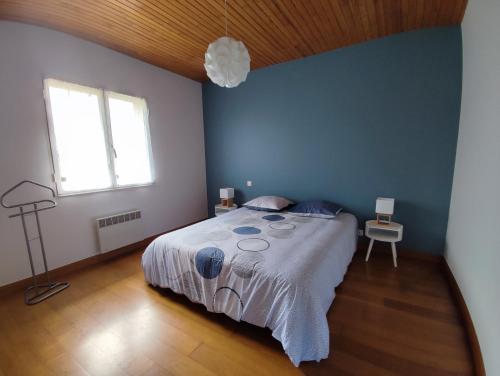une chambre avec un grand lit avec un mur bleu dans l'établissement Maison entre Terre et Mer, à Saint-Jean-de-Marsacq