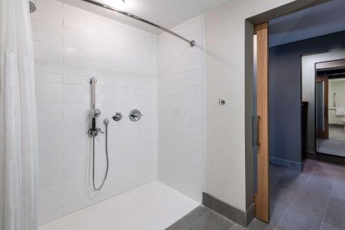 a bathroom with a shower with white tiles at Hilton Garden Inn Longmont in Longmont