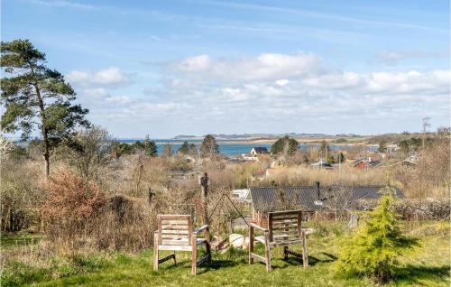 dos sillas y una mesa en un campo con el océano en 4 Bedroom Beautiful Home In Knebel, en Knebel