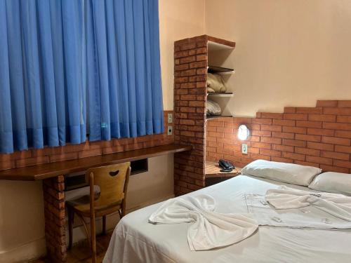 a bedroom with a bed and a blue curtain at Hotel Goiânia Palace in Goiânia