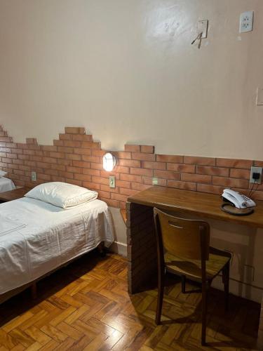 a bedroom with a bed and a desk with a phone at Hotel Goiânia Palace in Goiânia