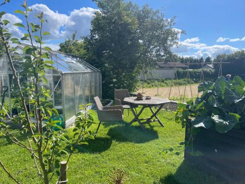 a garden with a table and a greenhouse at jygge- hyggelige Ferienwohnung in Nordborg