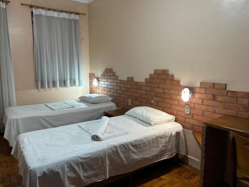 a room with two beds and a brick wall at Hotel Goiânia Palace in Goiânia