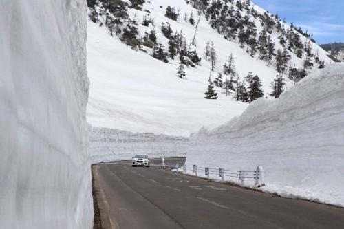 a car driving down a road next to snow covered mountains at ANA InterContinental Appi Kogen Resort by IHG in Hachimantai