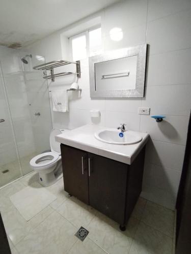 a white bathroom with a sink and a toilet at Hotel El Bosque Valledupar in Valledupar