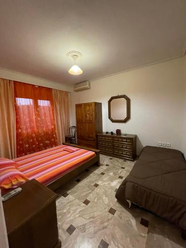 a bedroom with a bed and a dresser and a mirror at Katerina's house in Kalopigado